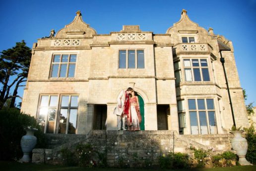 asian wedding couple kissing in front of old down manor wedding venue