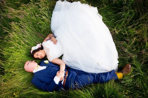 bride and groom laying on the grass