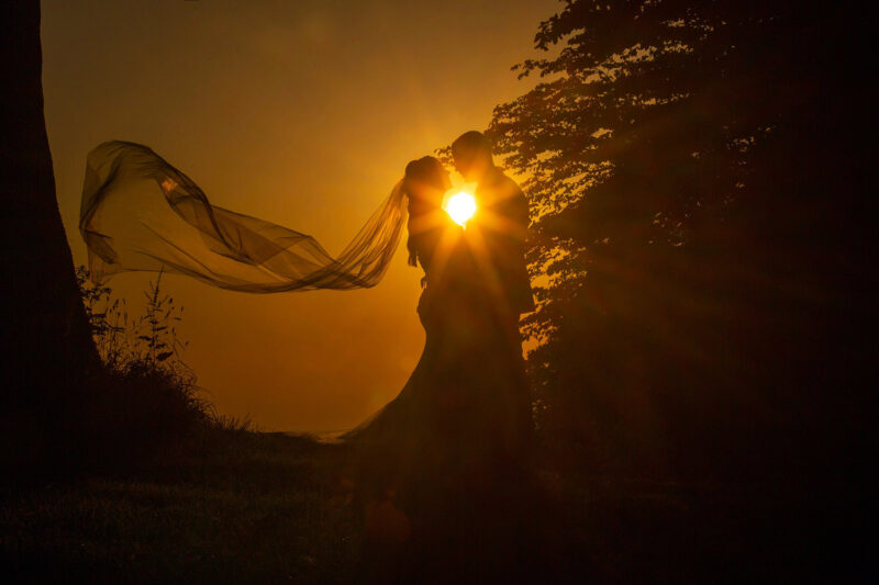 silhouette of the wedding couple with the setting sun between them