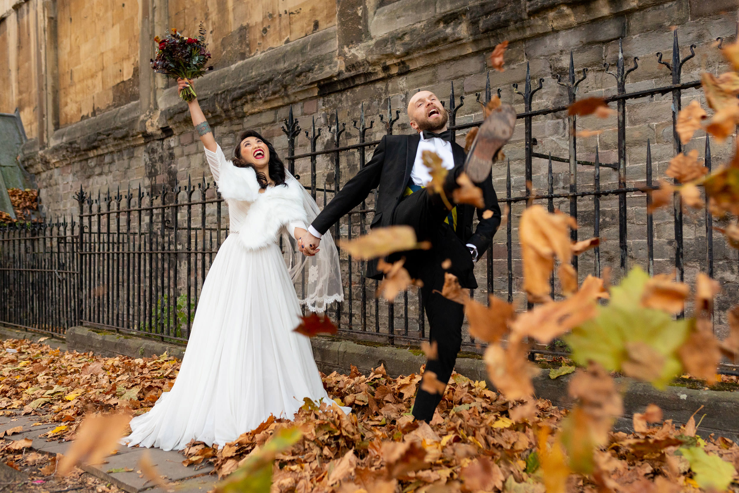 wedding couple kicking autumn leaves in bristol