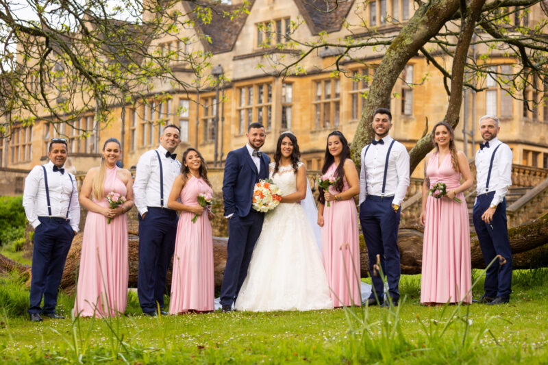 bridal party posing with coombe lodge in the background