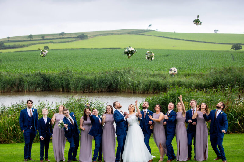 bridal party throwing flowers in the air at quantock lakes wedding venue