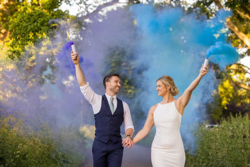 brider and groom walking holding hands and smoke bombs