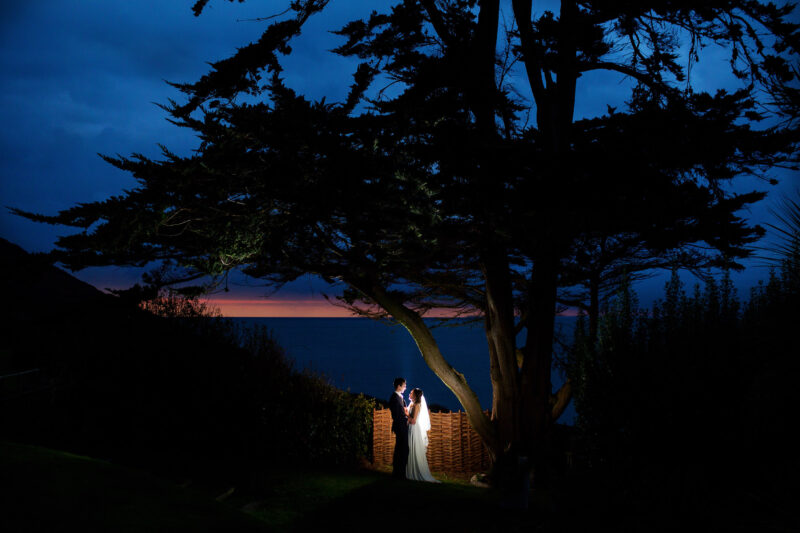 bride and groom kissing at dusk with the dark sky and sea behind at polhawn fort