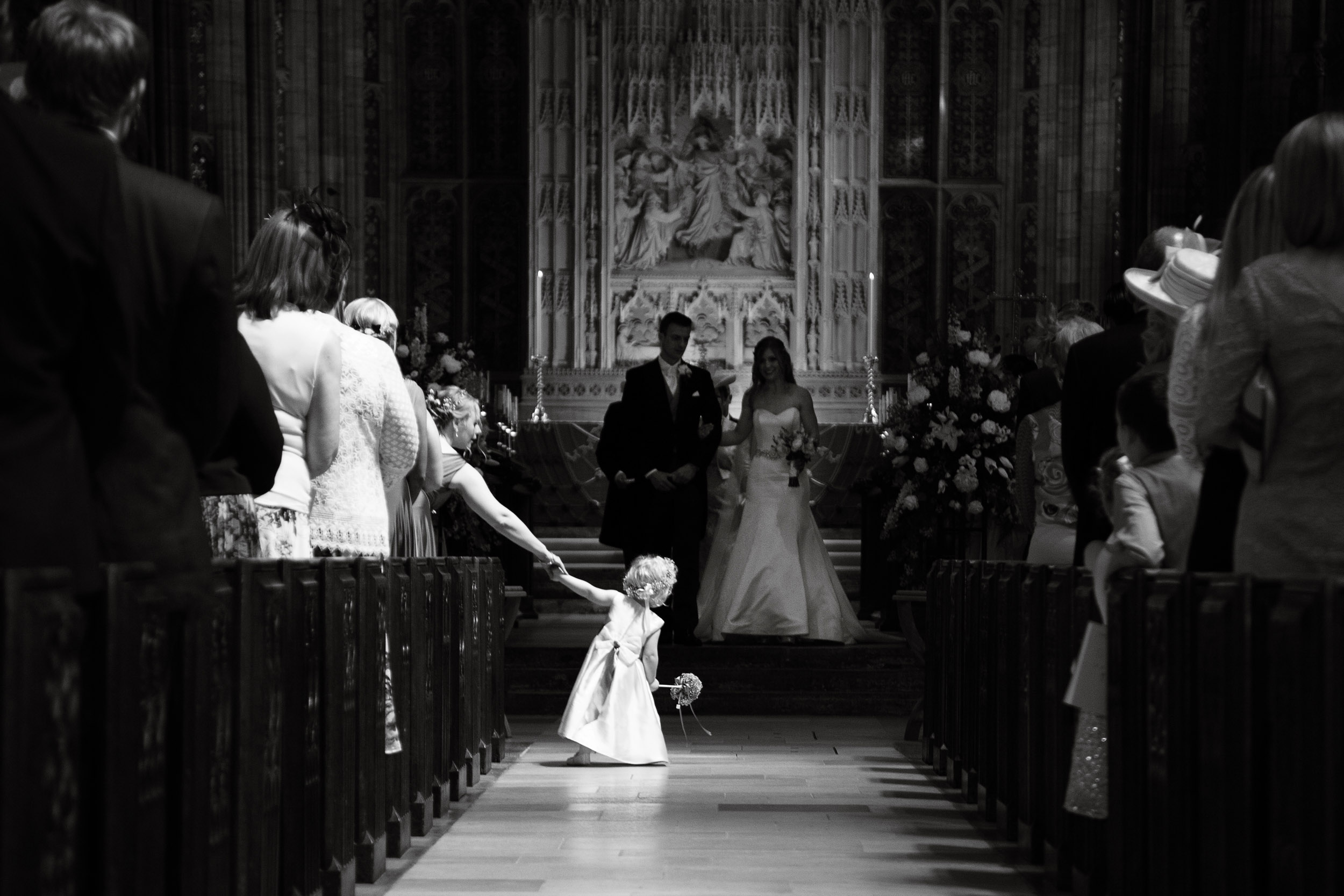 little flower girl looking at the bride and groom at sherborne abbey