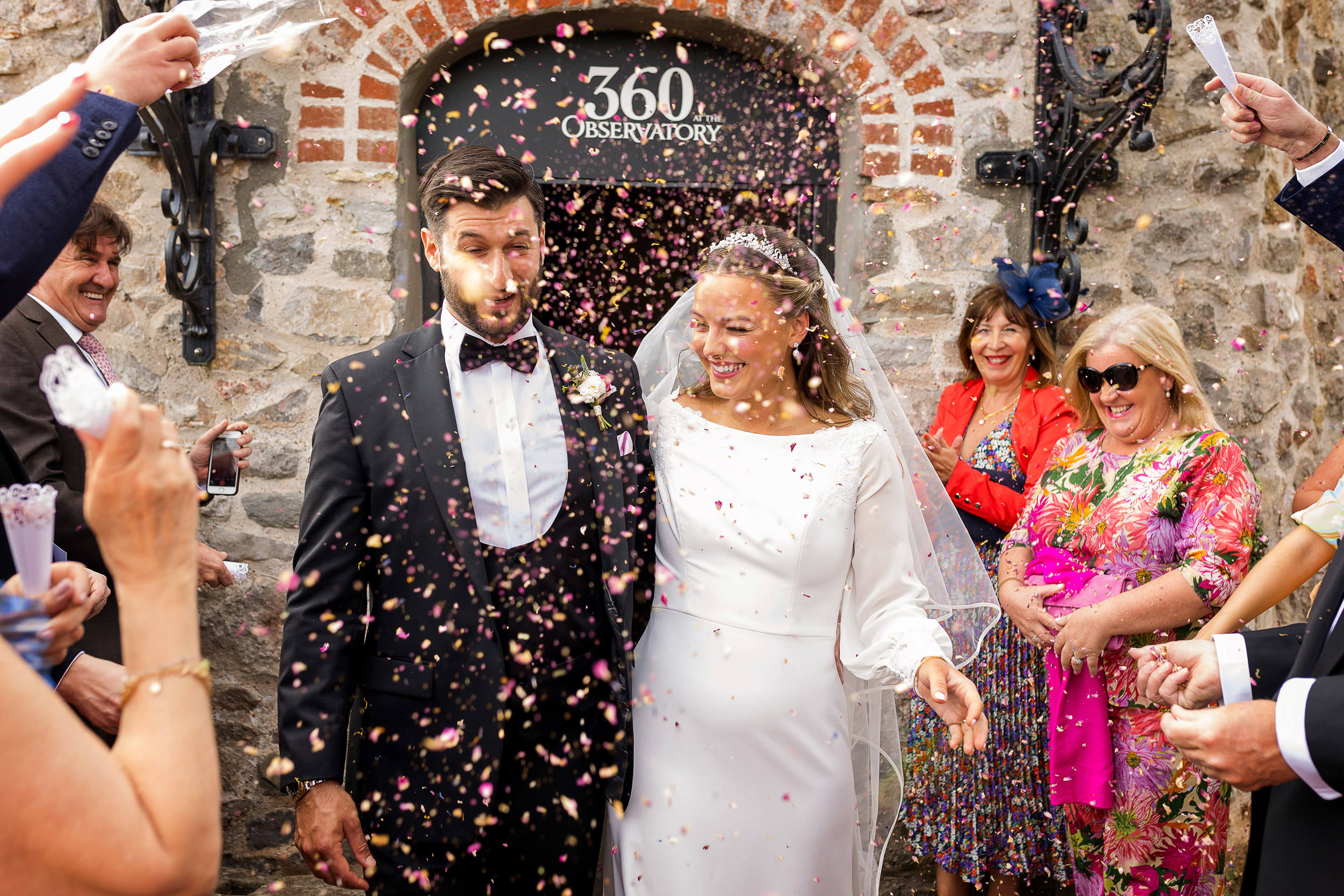 BRIDE AND GROOM WALKING THROUGH THE CONFETTI AT CLIFTON OBSERVATORY. CLIFTON OBSERVATORY WEDDING PHOTOGRAPHY