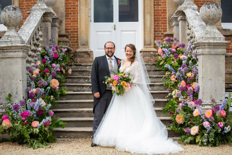 bride and groom standing in front of main entrance at crowcombe court wedding venue in somerset